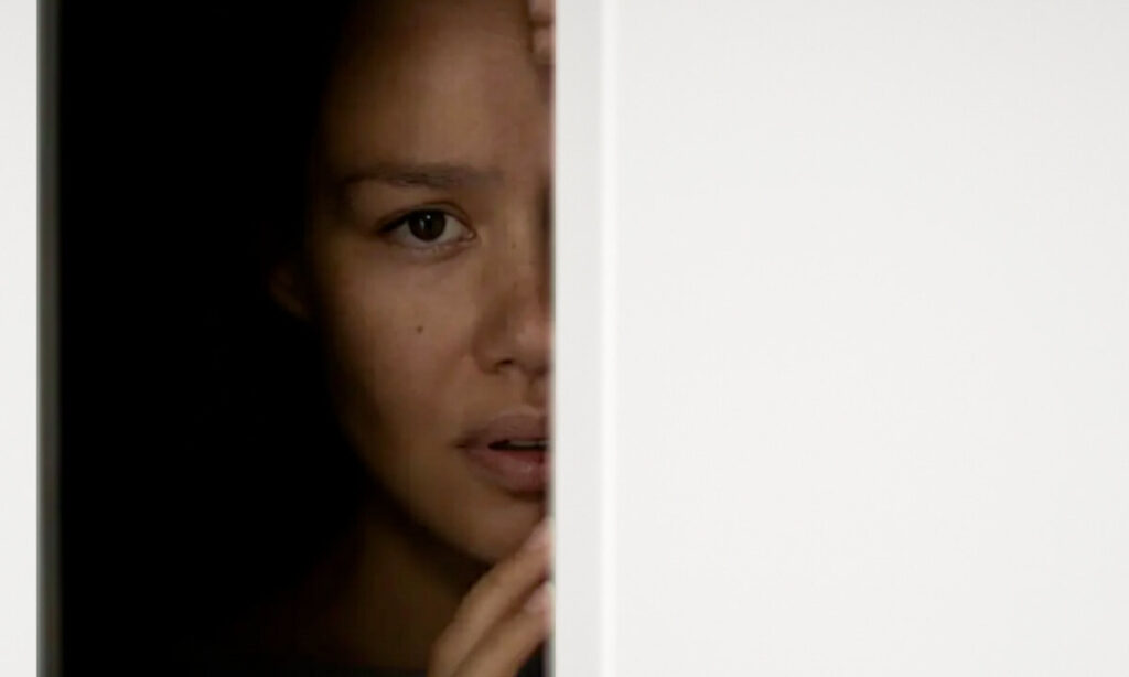 زن مضطرب که نیمی از چهره‌اش توسط دیوار سفید پنهان شده، نماد سوگ پنهان و اندوه نادیده گرفته شده.