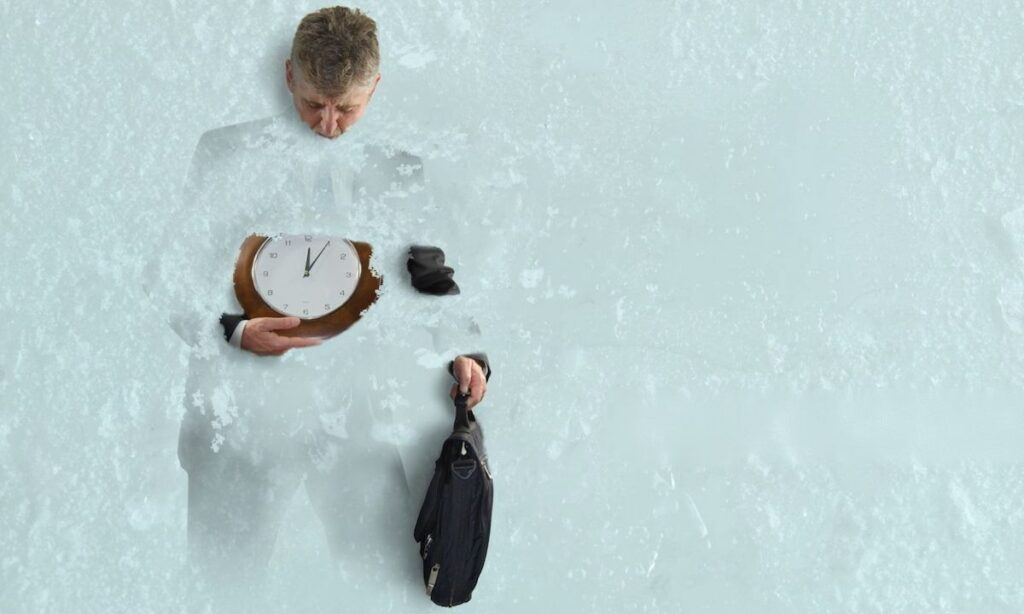 مردی که در برف و یخ در حال محو شدن است در حالی که ساعت و کیفی در دست دارد؛ نمادی از فرسودگی شغلی، احساس «یخ‌زده در زمان» و «گمشده در کار».