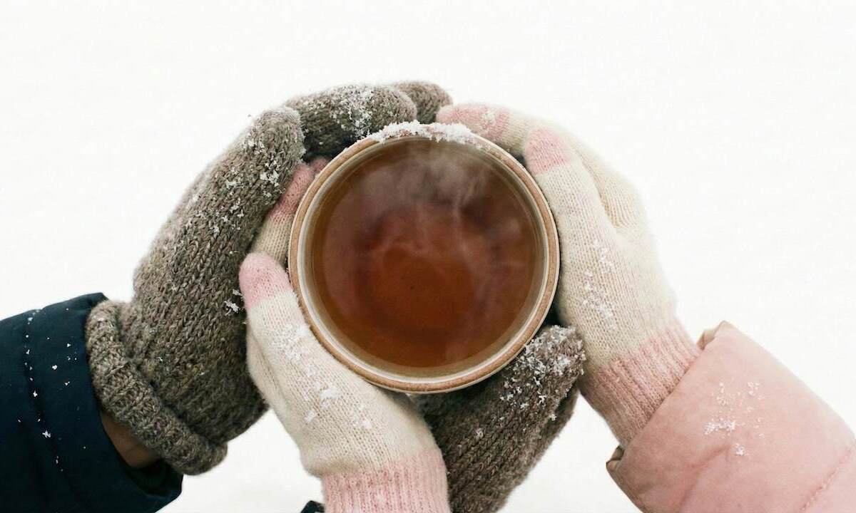 دستان زن و شوهری که به کمک هم یک فنجان چای داغ را در هوای برفی نگه داشته‌اند؛ نمادی از تلاش برای جلوگیری از سرد شدن رابطه و حفظ گرمای عشق.