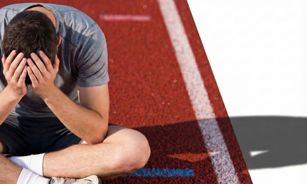 مرد دوندهای که با ناامیدی روی پیست نشسته است؛ تصویر مفهومی برای مقاله روانشناسی بازماندگان شکست و قفل شدن ذهن.