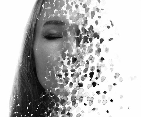 تصویری مفهومی از یک زن با چشمان بسته که نیمی از صورتش به ذرات کوچک تبدیل شده و در حال محو شدن است، نمادی از فرسودگی عاطفی و از دست دادن خود در روابط خاکستری.